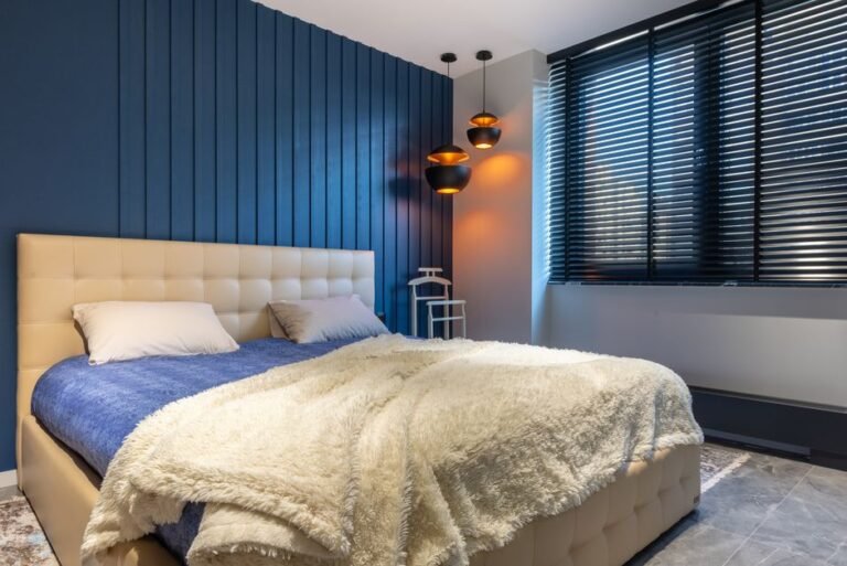 A bedroom with blackout curtains and cool, dim lighting
