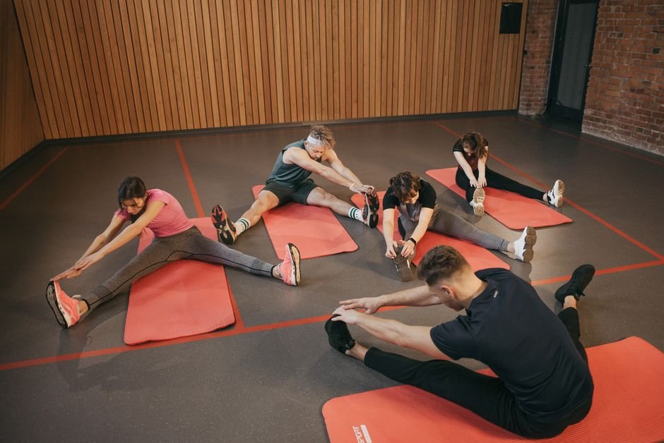 A group of people in a fitness class following an instructor's movements in a bright studio