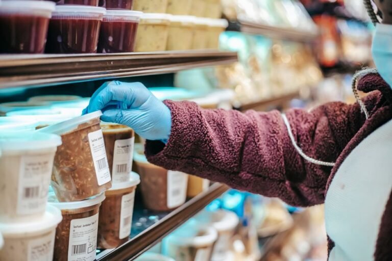 A hand holding a food package and reading the nutrition facts label on the back