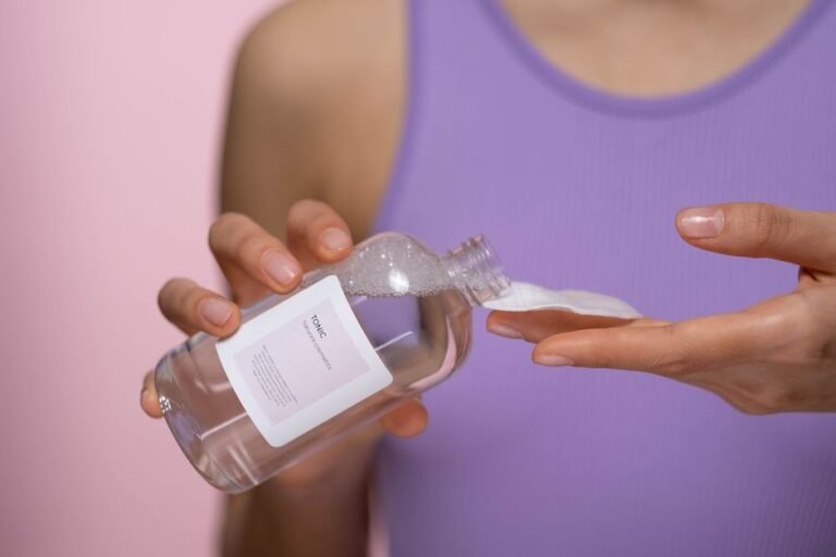 A bottle of micellar water beside a stack of round cotton pads on a bathroom counter