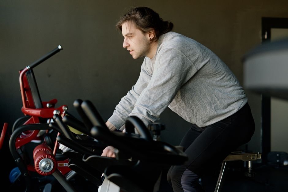 A person in a t-shirt and shorts riding a stationary bike in an ordinary gym