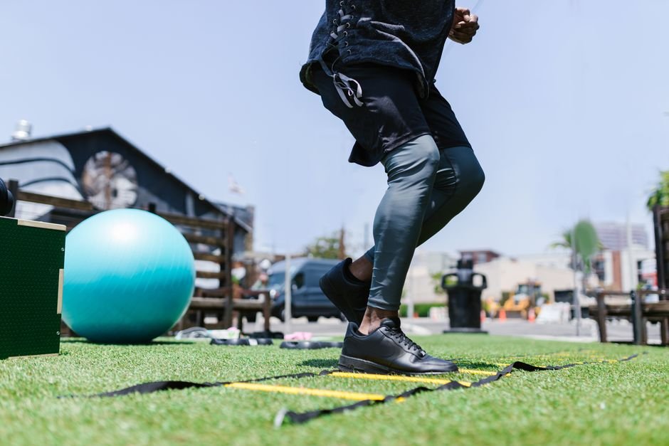 A person performing a kettlebell carry in a gym, holding weights at their sides while walking