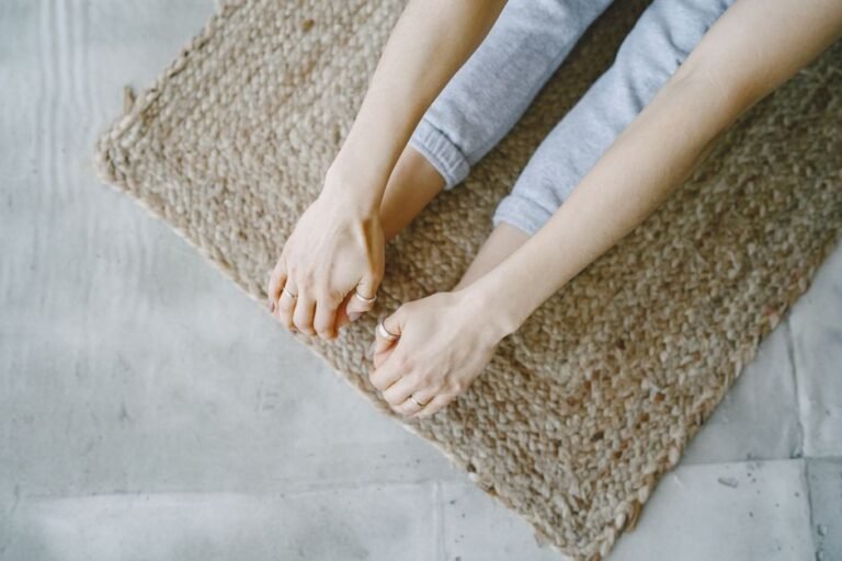 Person doing a gentle seated yoga stretch on a mat at home