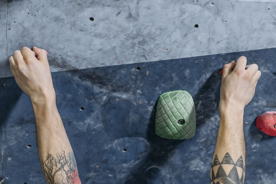 A person doing a dead hang from a pull-up bar to build grip strength