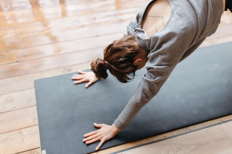 Person practicing a modified Downward Dog pose with bent knees on a yoga mat