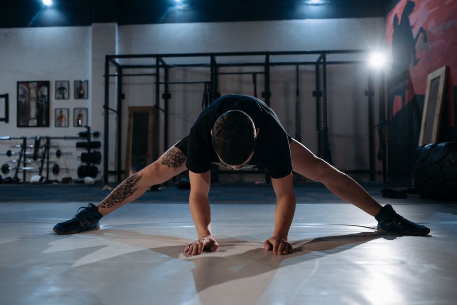 A person doing a leg swing stretch on a gym floor before starting a workout