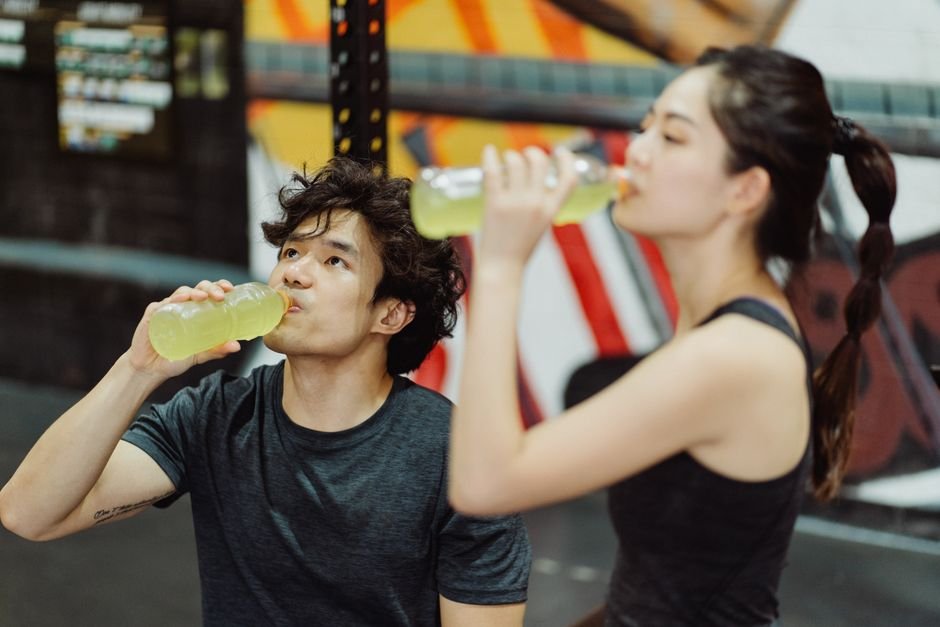A person drinking from a water bottle with an electrolyte mix after a workout