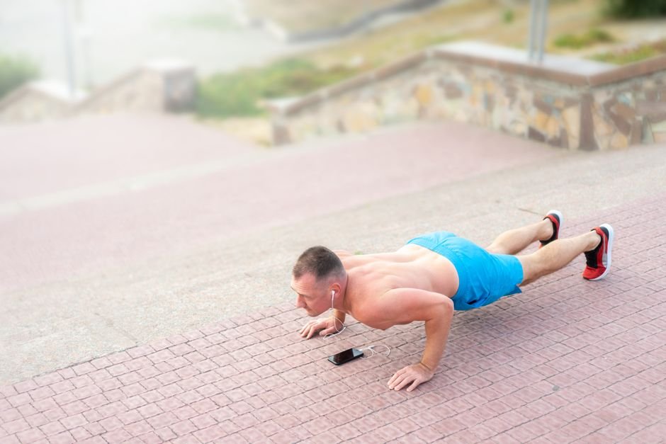 A person mid-exercise wearing headphones, focused on the pace of their movement
