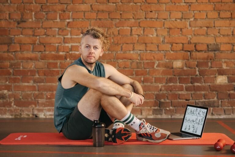 A person writing in a workout log notebook next to a set of dumbbells