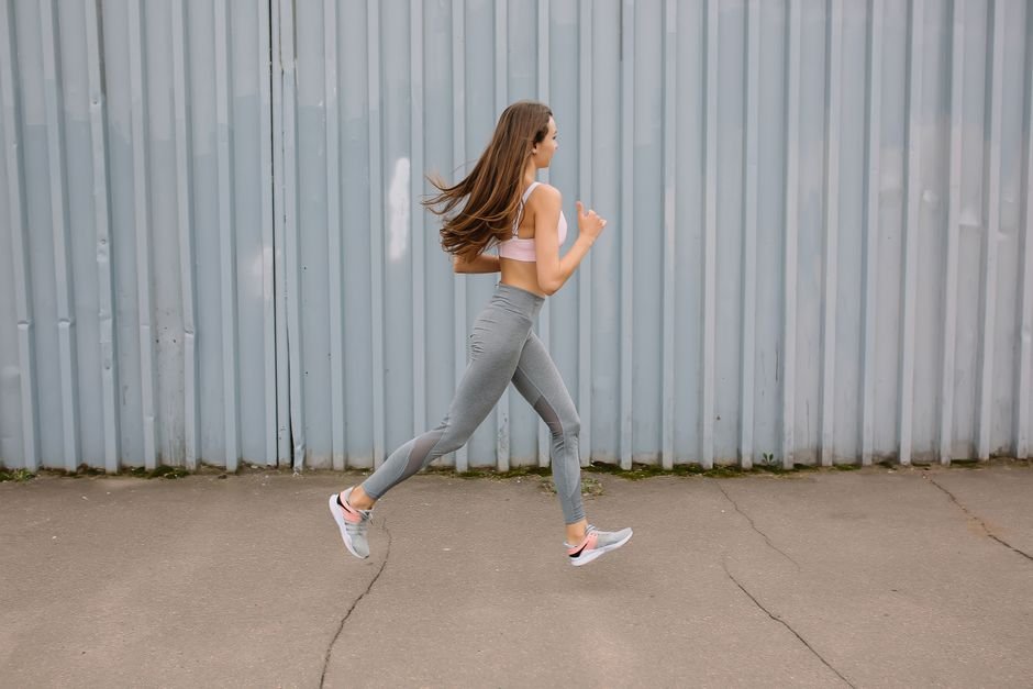 A person jogging on an outdoor path with one hand briefly pressed to their side