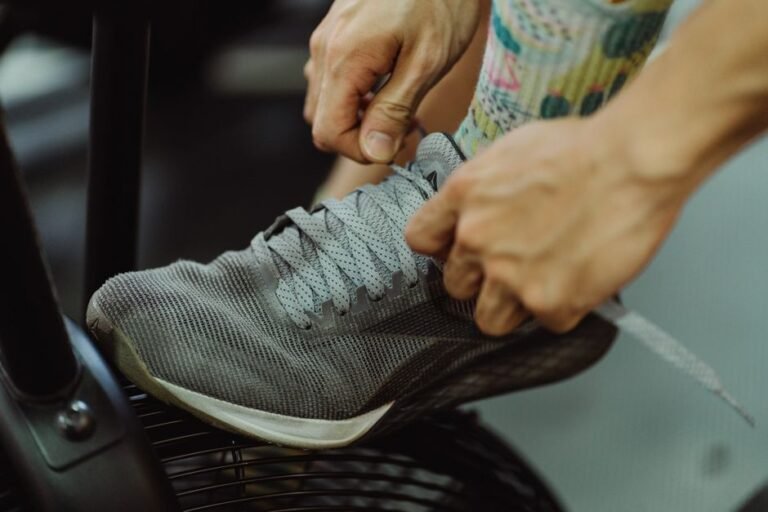 A person sitting on a bench lacing up athletic shoes before exercising