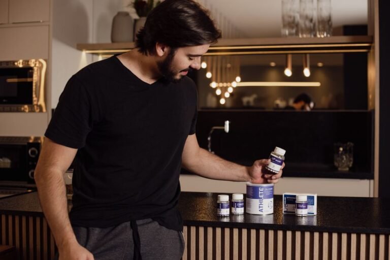 A person standing in a kitchen turning a small bottle over to read the label on the back
