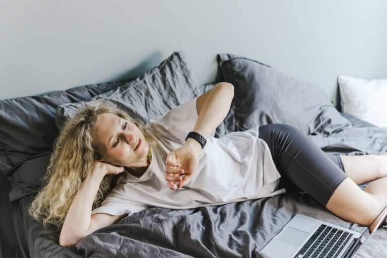 A person sitting comfortably on a couch in workout clothes, water bottle nearby, on a rest day