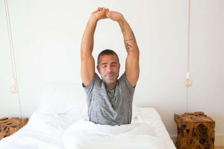 A person waking up and stretching in bed with morning light