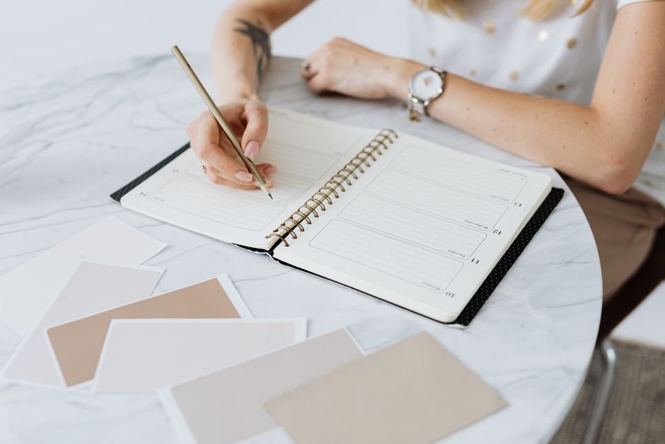 A person writing in a planner next to a water bottle and workout gear