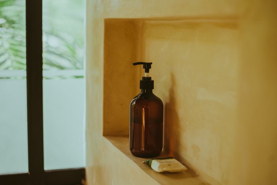 A skincare dropper bottle standing on a bathroom shelf next to other products