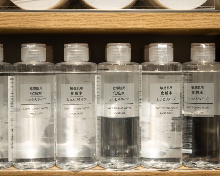 Skincare bottles and jars stored upright on a shelf inside a closed cupboard