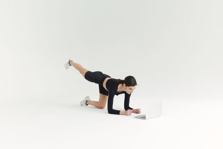Folded leggings, a t-shirt, socks, and trainers laid out on a wooden floor beside a gym bag