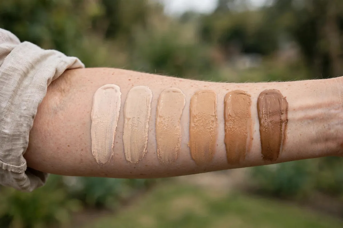 Foundation shade swatches in different skin tones on a forearm for choosing foundation online